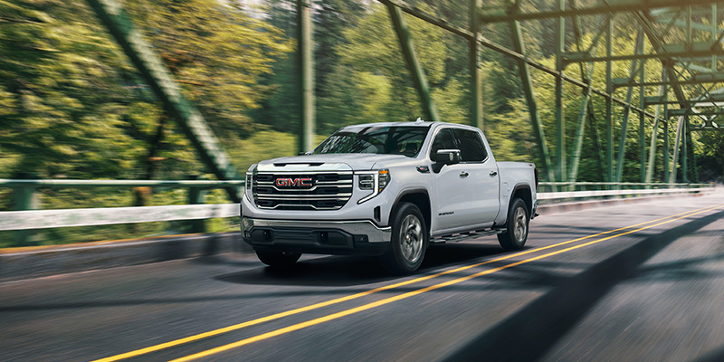 2026 GMC Sierra 1500 being driven across a green countryside bridge